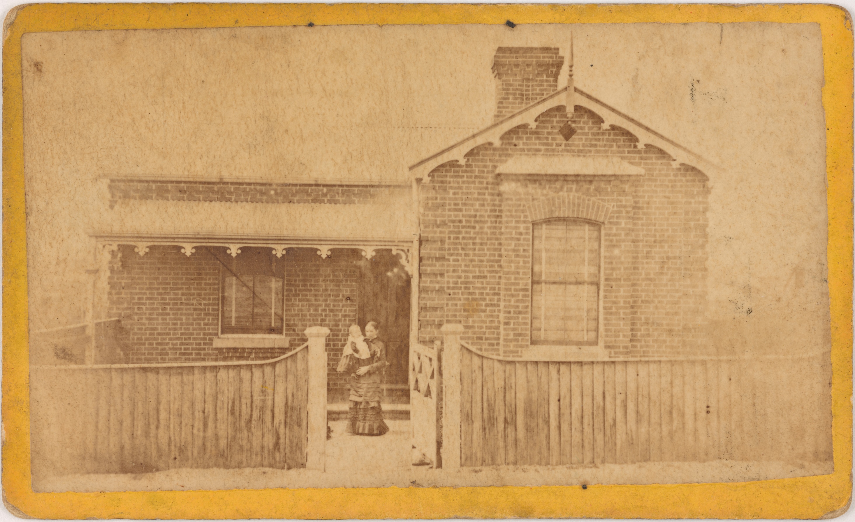 Young woman and infant in front of an unidentified brick cottage, around 1875 / American Photo Company, F. Stubbs & Co.